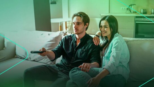 Casal assistindo TV confortavelmente no sofá.