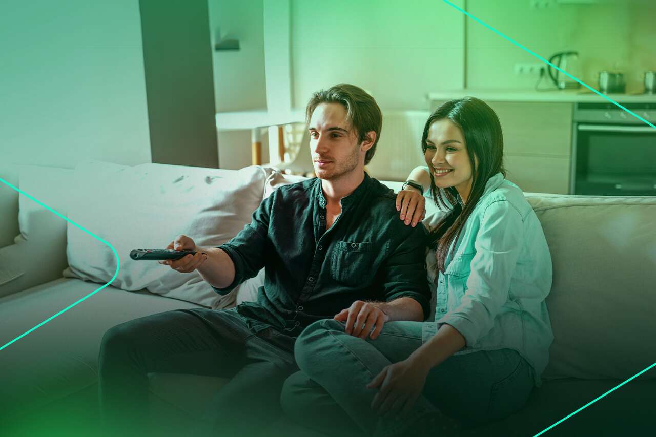 Casal assistindo TV confortavelmente no sofá.