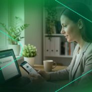 Mulher usando smartphone e laptop em ambiente moderno.