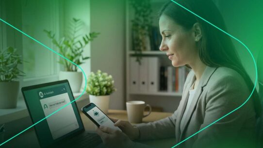 Mulher usando smartphone e laptop em ambiente moderno.