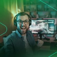 Homem sorrindo e jogando no computador com fones
