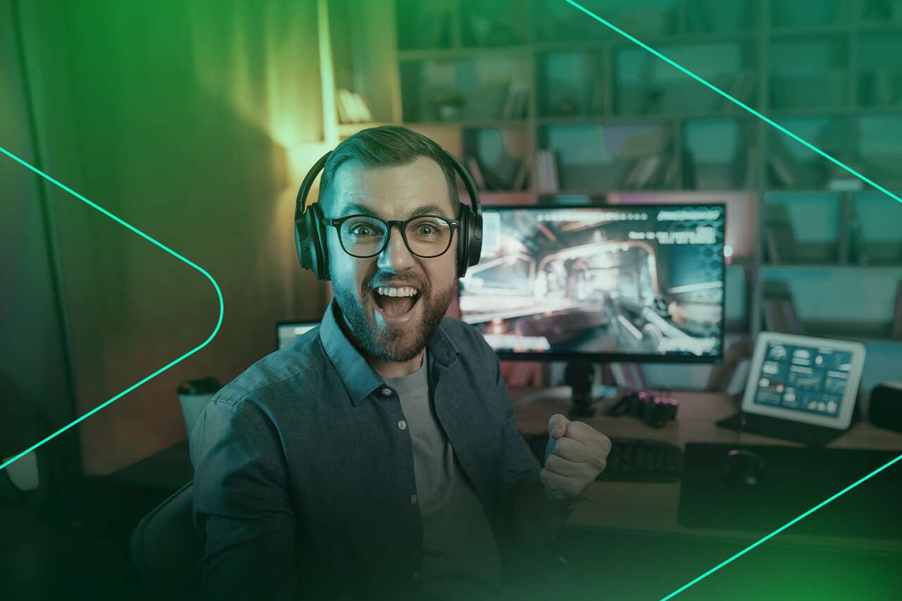 Homem sorrindo e jogando no computador com fones