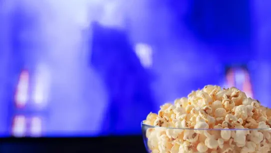 Televisão com um balde de pipoca e controle acima da mesa