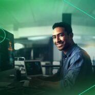 Homem sorrindo enquanto trabalha em computador
