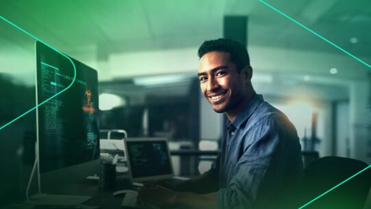 Homem sorrindo enquanto trabalha em computador