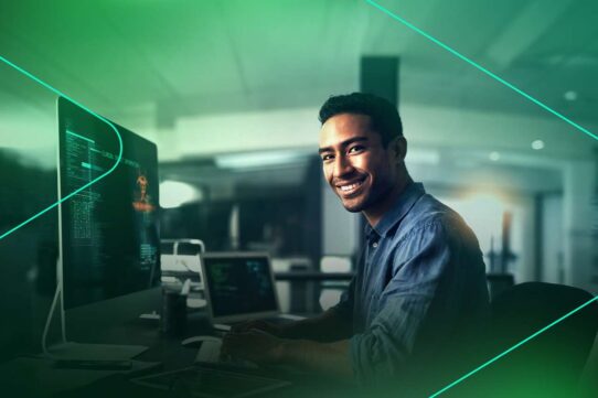 Homem sorrindo enquanto trabalha em computador