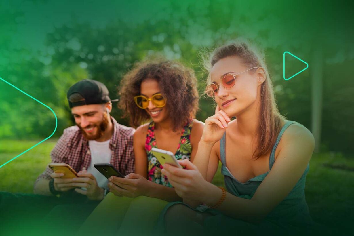 Três amigos usando smartphones ao ar livre