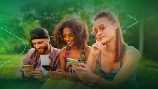 Três amigos usando smartphones ao ar livre