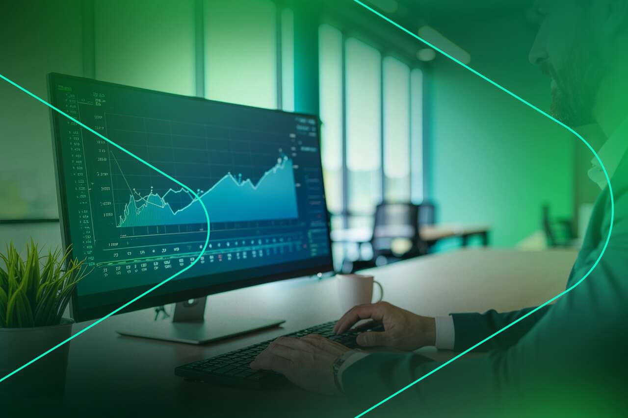 Homem analisando gráficos em monitor de escritório moderno.