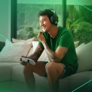 Jovem sorrindo enquanto joga videogame em casa