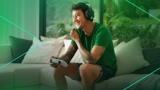 Jovem sorrindo enquanto joga videogame em casa