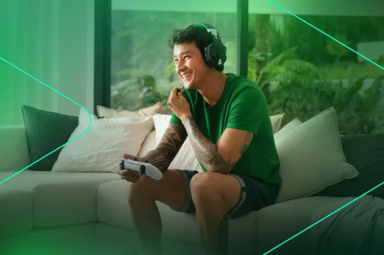 Jovem sorrindo enquanto joga videogame em casa
