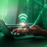 Homem usando smartphone e laptop com sinal de Wi-Fi