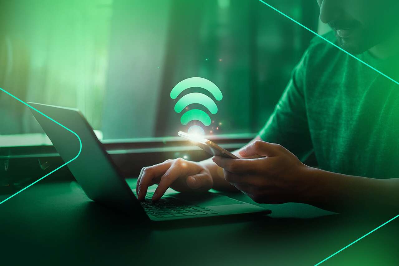 Homem usando smartphone e laptop com sinal de Wi-Fi