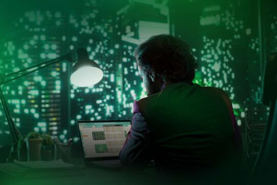 Homem trabalhando em laptop com fundo urbano iluminado