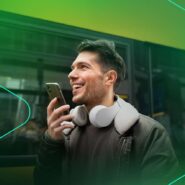 Homem sorrindo enquanto fala ao celular na rua.