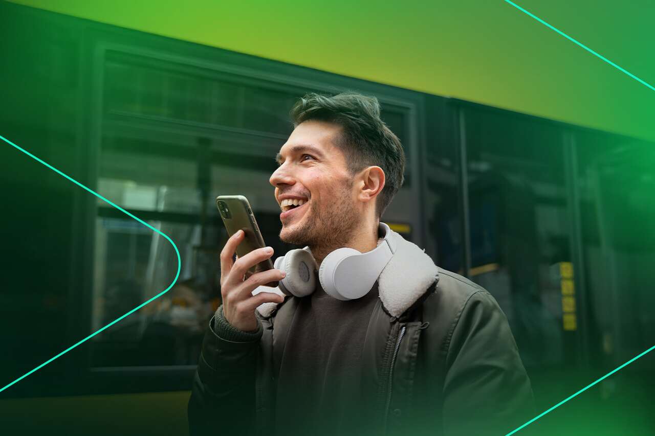 Homem sorrindo enquanto fala ao celular na rua.