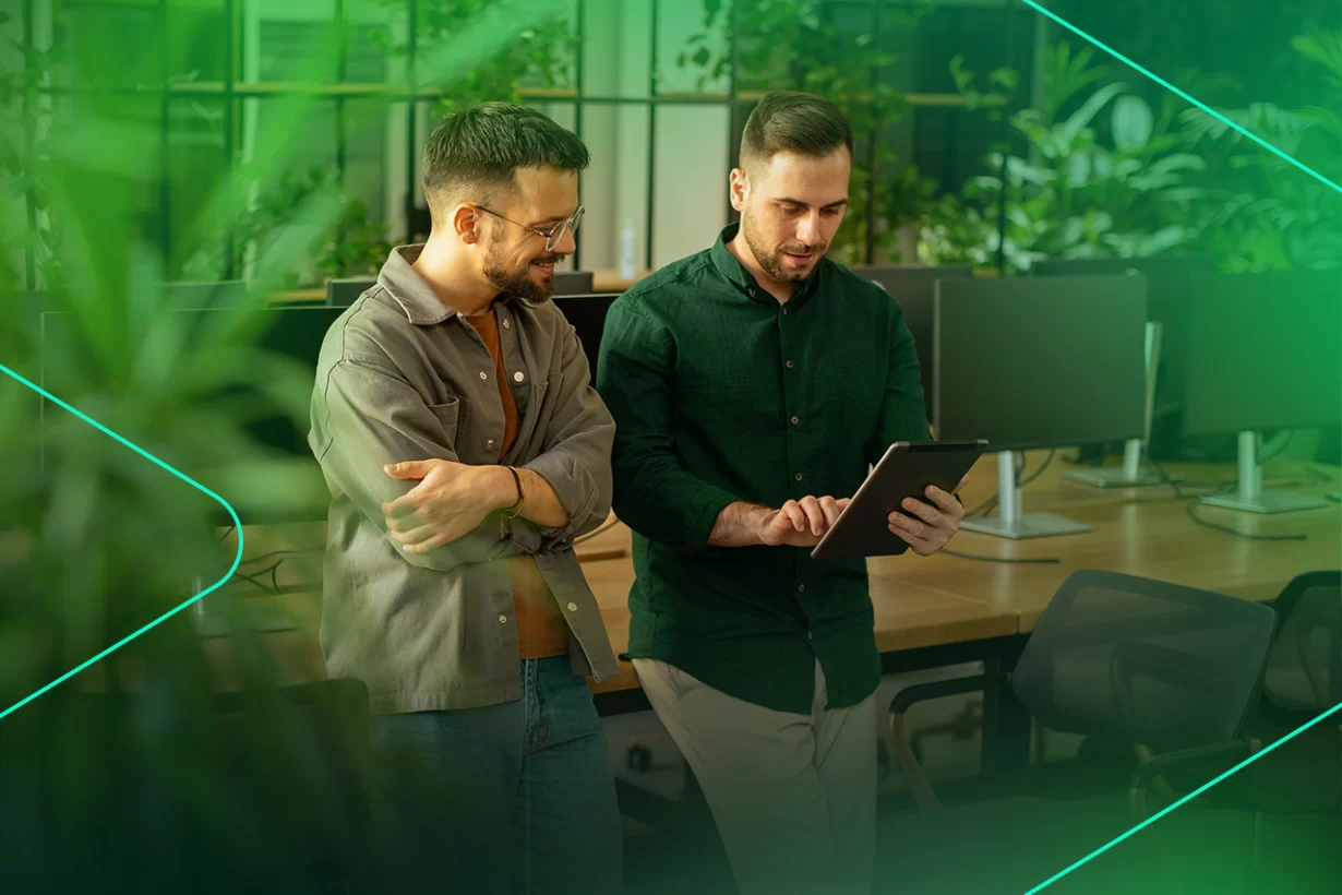 Dois homens analisam dados em tablet em ambiente moderno.