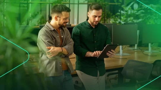 Dois homens analisam dados em tablet em ambiente moderno.