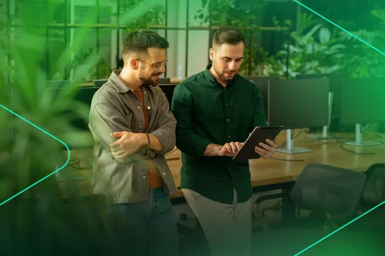 Dois homens analisam dados em tablet em ambiente moderno.