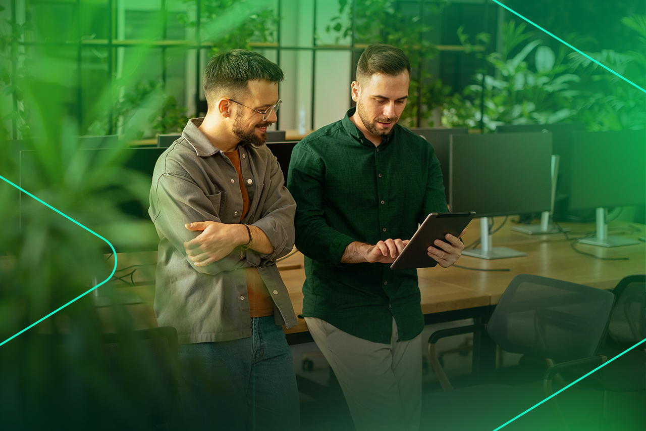 Dois homens analisam dados em tablet em ambiente moderno.