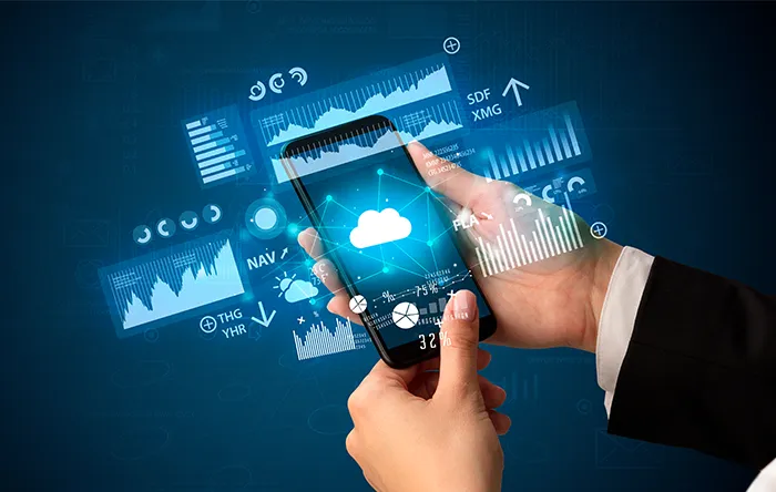 Mão segura smartphone exibindo ícone de nuvem cercado por gráficos digitais e análises financeiras azuis.