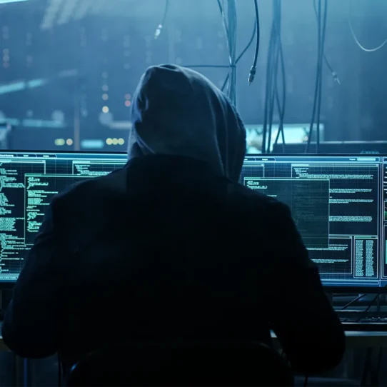 Homem encapuzado interagindo com computadores
