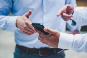 Duas pessoas conversando e apontando para um celular