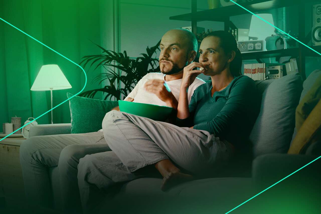 Casal assistindo filme em casa com pipoca
