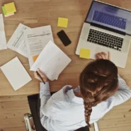 Mulher interagindo com papéis e notebook