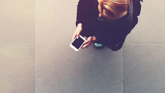 Mulher interagindo ao celular, com o ângulo acima dela.