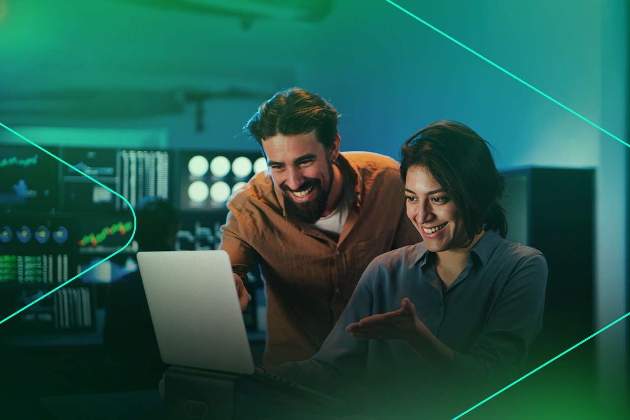 Duas pessoas sorrindo enquanto trabalham em um laptop.