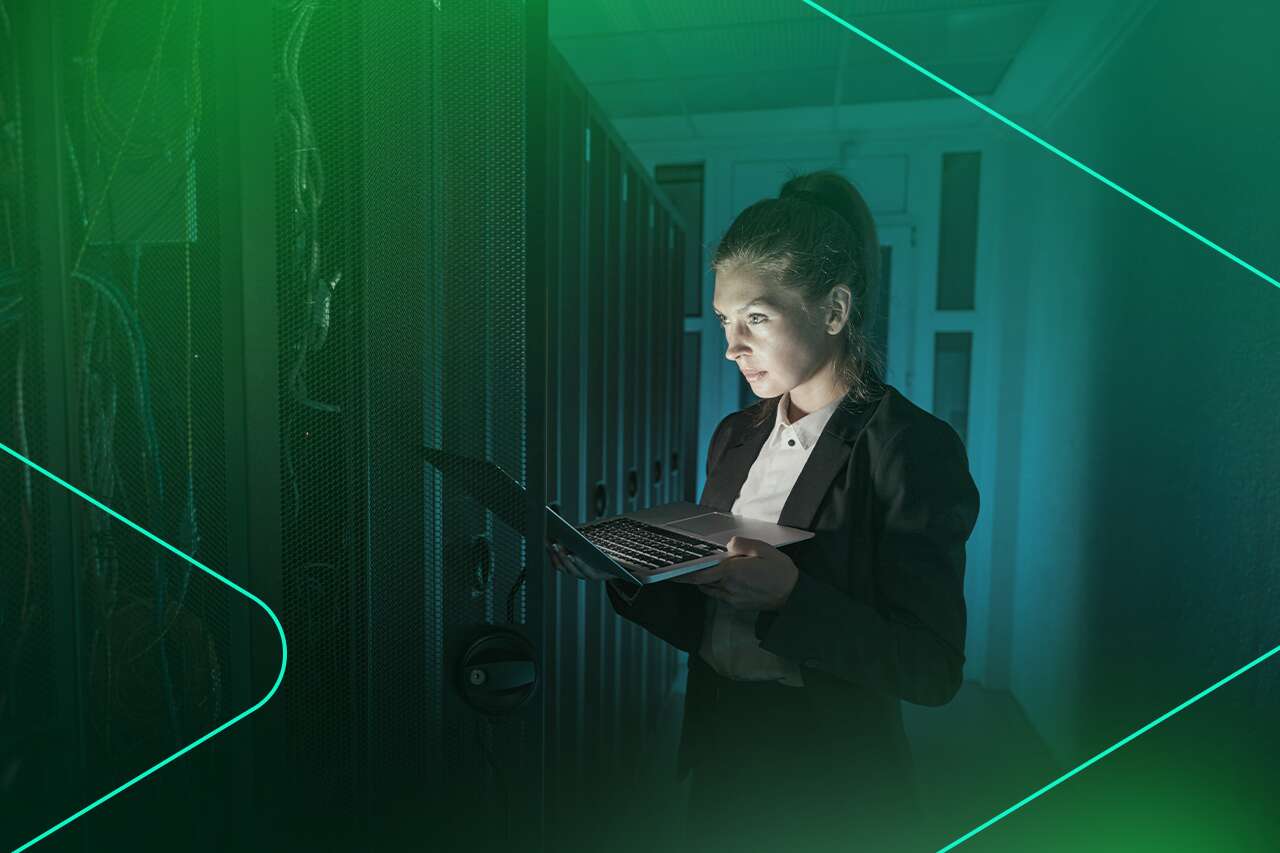 Mulher usando laptop em sala de servidores