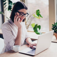Mulher conversando ao telefone e interagindo com o notebook