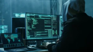 Homem encapuzado trabalhando em terminais de computador