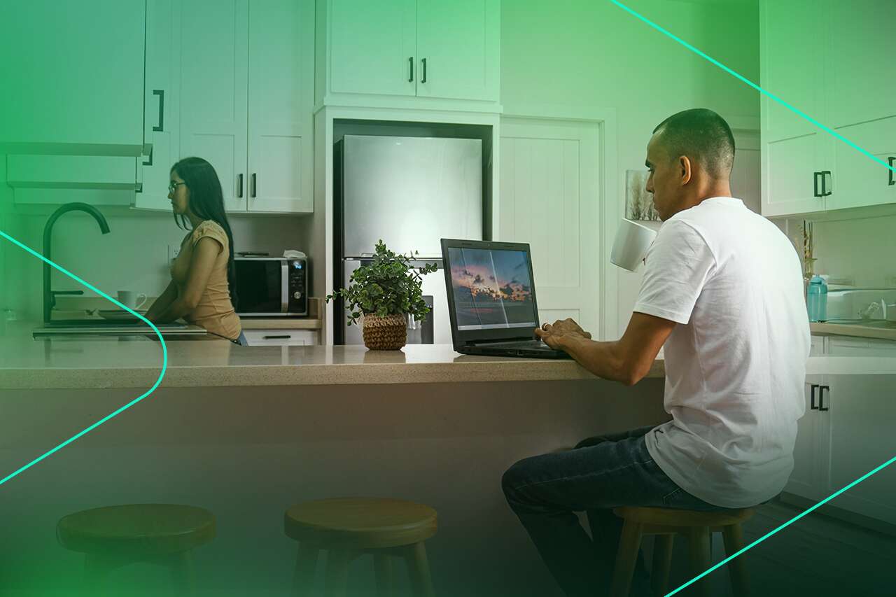 Homem trabalhando no laptop em cozinha moderna.