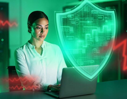 Mulher usando laptop com escudo de proteção digital.