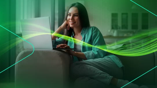 Mulher sorrindo enquanto usa laptop em casa