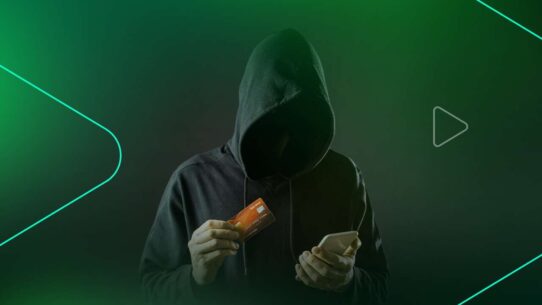 Pessoa encapuzada segurando cartão e celular
