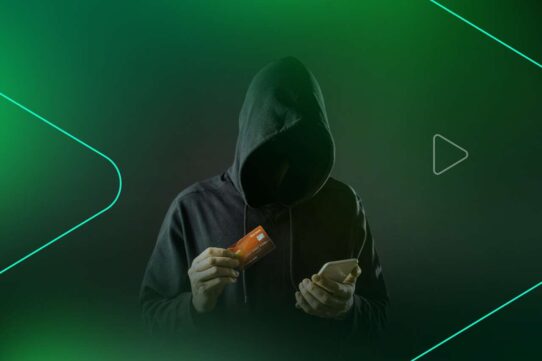 Pessoa encapuzada segurando cartão e celular