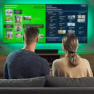 Casal assistindo televisão em ambiente moderno.
