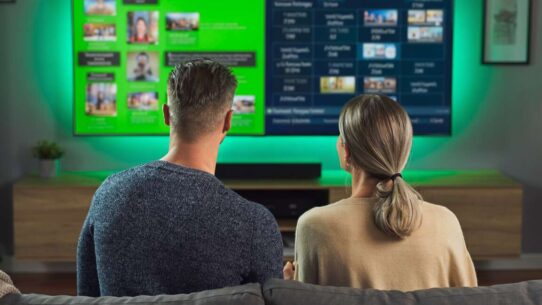 Casal assistindo televisão em ambiente moderno.