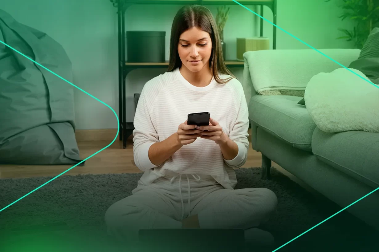 Mulher sentada no chão usando smartphone em casa