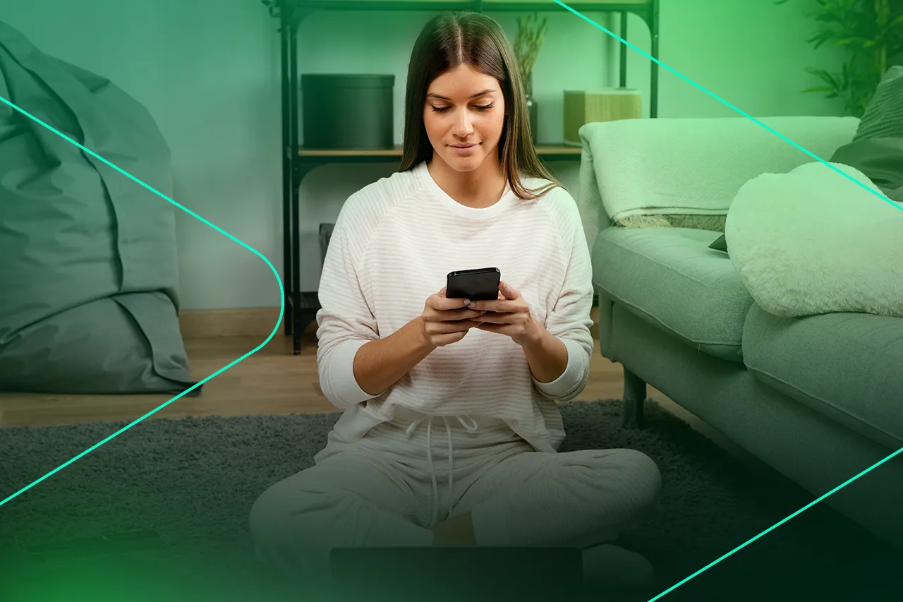 Mulher sentada no chão usando smartphone em casa