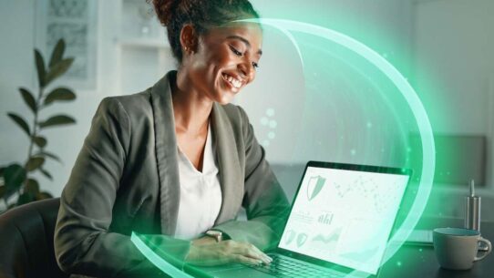 Mulher sorrindo enquanto usa laptop em ambiente de trabalho