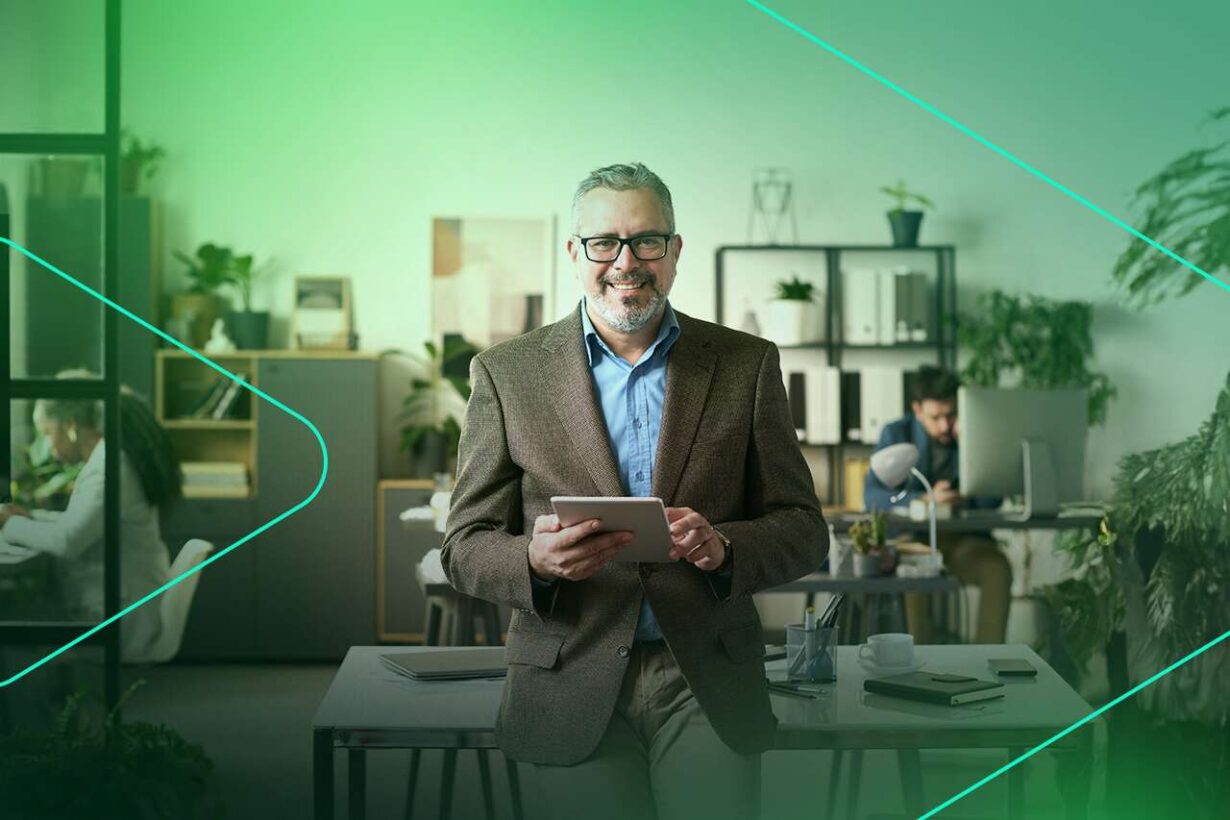 Homem sorrindo em escritório moderno com tablet.