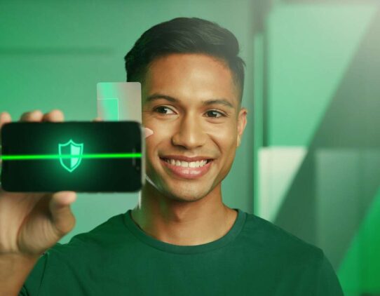 Homem sorrindo enquanto segura um smartphone com ícone de segurança.