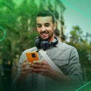 Homem sorrindo enquanto usa celular na rua