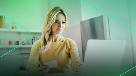 Mulher usando laptop e cartão de crédito em casa