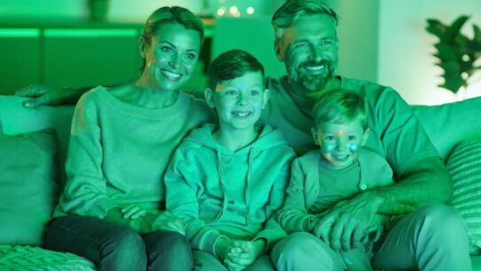 Família feliz assistindo TV em ambiente iluminado.
